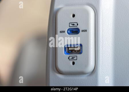 USB-Anschluss am Sitz des Flugzeugs zum Aufladen der elektronischen Geräte auf Reisen Stockfoto