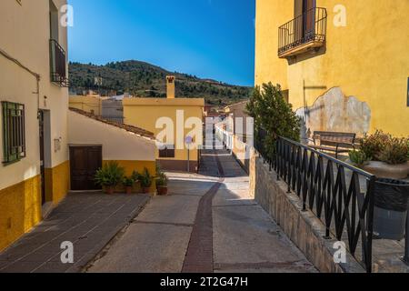 Ein Weitwinkelfoto einer spanischen Dorfstraße, die zum Fuß eines Berges führt. Stockfoto