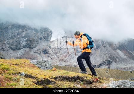 Running caucasian man mit Rucksack und Trekkingstöcken an der Makalu Barun Park Route in der Nähe von Khare. Mera Peak Klettern Akklimatisierung aktiv Walk. Rucksack Stockfoto