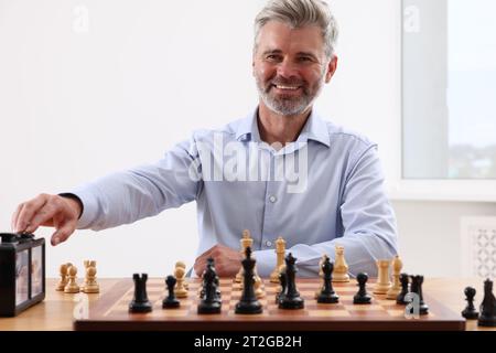 Mann, der während des Turniers am Tisch drinnen die Schachuhr anschaltet Stockfoto