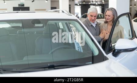 Ein älteres kaukasisches Paar wählt ein neues Auto in einem Autohändler. Stockfoto