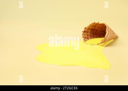 Geschmolzenes Eis und Waffelkegel auf gelbem Hintergrund, Platz für Text Stockfoto