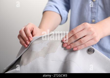 Frau zeigt Flecken vom Kaffee auf der Jacke vor verschwommenem Hintergrund, Nahaufnahme Stockfoto