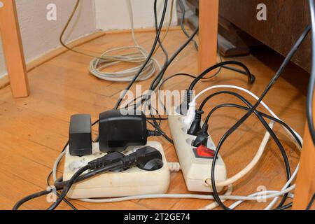 Verwickelte Kabel im Verlängerungskabel. Unordentliche Kabel. Kabel verheddern sich auf Parkettböden. Stockfoto