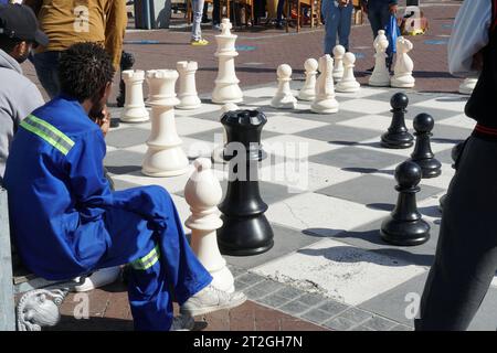 Lokale Spieler genießen eine Partie Straßenschach mit Riesenfiguren an der Waterfront in Kapstadt Südafrika. Stockfoto