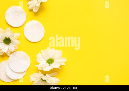 Composition with cotton pads and chamomile flowers on yellow background Stock Photo