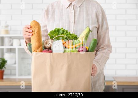 Frau und Papiertüte mit verschiedenen Produkten in der Küche Stockfoto