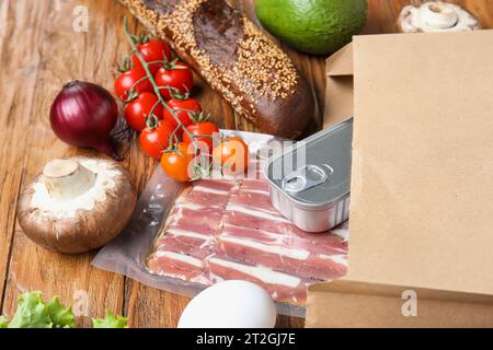 Papiertüte mit verschiedenen Produkten auf Holzhintergrund Stockfoto