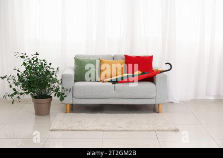 Bunte Sonnenschirme und Kissen auf dem Sofa im Zimmer Stockfoto