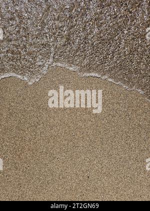 Direkt über dem Blick auf sanfte Wellen, die über Sand am Strand Rollen Stockfoto