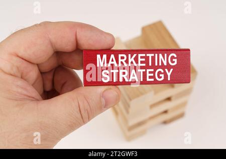 Geschäftskonzept. In den Händen eines Mannes befindet sich ein roter Holzteller mit der Inschrift - MARKETINGSTRATEGIE Stockfoto