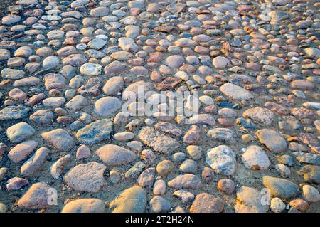Die Textur der Steinstraße, Pflaster, Wände aus großen grauen alten mittelalterlichen runden starken Steinen, Kopfsteinpflaster. Der Hintergrund. Stockfoto
