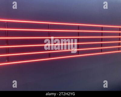 Neonstreifen, Beleuchtung. Rote Streifen an einer schwarzen Decke. Leuchtendes Neon, dekorative Tafeln, Elektrokonstruktion, U-Bahn-Dekoration. Stockfoto