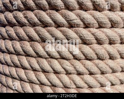 Textur, Hintergrund. Ein starkes, festes Seil ist auf einer Rolle aufgewickelt. Garn zum Binden aus strapazierfähigem braunem Material. Gewinde werden aus dem Seil gezogen. Stockfoto