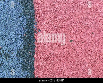 Blau-rosa Textur, Steine in verschiedenen Farben. Ein Hintergrund aus kleinen, rosa und blauen Steinen, die dicht auf der Straße verpackt sind. Sportplatz floori Stockfoto
