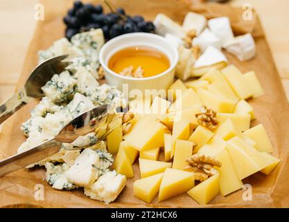 Käseplatte mit Blauschimmelkäse, Honig und Trauben auf Holztisch. Großer Haufen Käse. Stockfoto