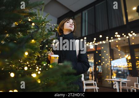 Niedliches Teenager-Mädchen mit Kaffee zum Mitnehmen am kalten Wintertag. Teenager-Kind trinkt heißes Getränk an kühlen Tagen. Stockfoto