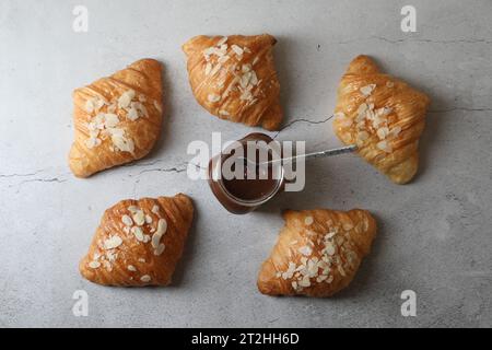 Leckere Croissants mit Mandelflocken und Schokoladenpaste auf grauem Tisch, flach gelegt Stockfoto