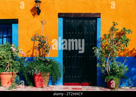 Helle Außenfassade eines Gebäudes in Marbella, Spanien. Alte schwarze Tür und bunte Wand. Stockfoto