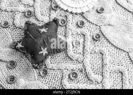 Schöne Textur eines weichen, warmen Naturpullovers, Strickstoffe und rote kleine runde Knöpfe zum Nähen und ein Nadelpolster. Flache Lagen. Der Hintergrund. Stockfoto