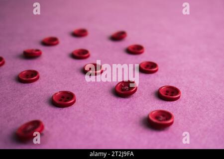 Schöne Textur mit vielen runden rosafarbenen Knöpfen zum Nähen, Handarbeiten. Kopierbereich. Flache Lagen. Rosa, lila Hintergrund. Stockfoto