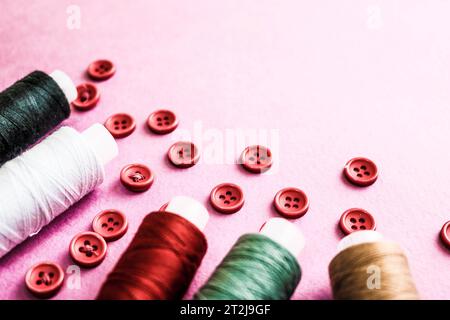 Schöne Textur mit vielen runden roten Knöpfen zum Nähen, Handarbeiten und Fadenspulen. Kopierbereich. Flache Lagen. Rosa, lila Hintergrund. Stockfoto
