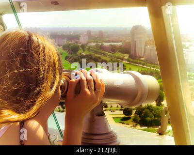 Ein hübsches Mädchen sieht die Landschaft, ein Panorama der Stadt im Beobachtungsraum, ein Fernglas, ein Teleskop mit einem Rechnungsannahme auf einem Stockfoto