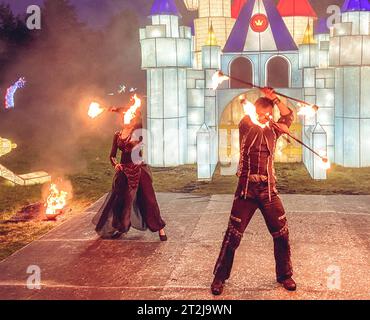 Feuershow, Tanz mit Flamme, männlicher Meister, der Feuer bläst, Auftritt im Freien, Flammenkontrolle Mann tanzt mit Feuer, mit Feuerspuren auf einem Backgro Stockfoto