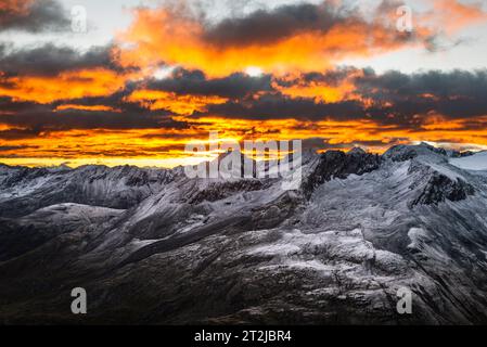 Leuchtende Wolken bei Sonnenaufgang über dem Ramolhaus mit Blick auf den wolkenbedeckten Hauptkamm der Ötztaler und Stubaier Alpen, Gurgler Tal, Ötztaler Alpen, Tirol Stockfoto