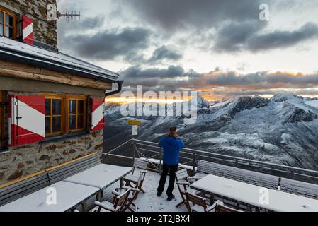 Mann fotografiert leuchtende Wolken bei Sonnenaufgang über dem Ramolhaus mit Blick auf den wolkenbedeckten Hauptkamm der Ötztaler und Stubaier Alpen, Österreich Stockfoto