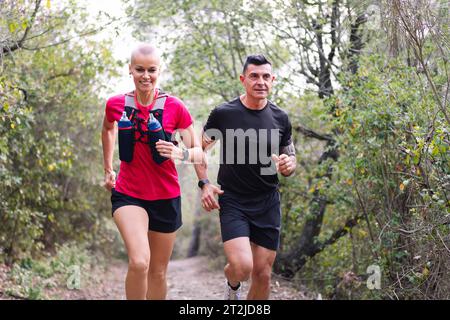Ein Paar, das Trailrunning im Wald übt Stockfoto