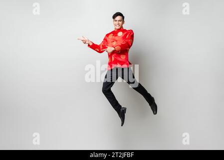 Porträt von lächelnd gut aussehenden asiatischen Mann in traditionellen chinesischen Kleidung Lächelnd und mit den Händen den Raum im Licht zur Seite zu leeren Grau isoliert Studio Bac Stockfoto