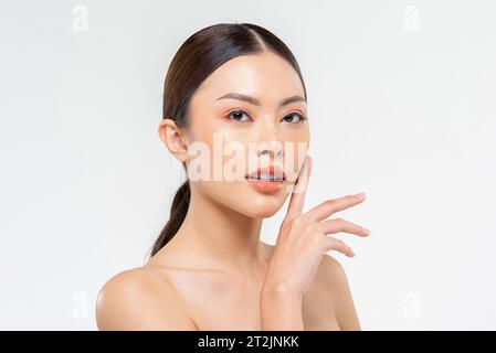 Schönheitsaufnahme Porträt einer attraktiven asiatischen Frau, die glatte Haut auf der Wange im weißen isolierten Studiohintergrund berührt Stockfoto