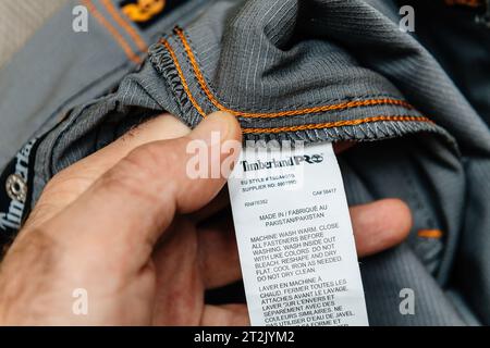 Hamburg, Deutschland - 16. Februar 2022: Eine männliche Hand, die Timberland Pro Arbeitshose hält, Made in Pakistan. Waschanleitung in Englisch und Französisch Stockfoto