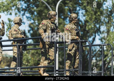 16.08.2023 Warschau, Polen. Mehrere moderne Soldaten stehen während der Militärparade auf einer Plattform. Verschwommene Bäume im Hintergrund... Spezialeinsatzkommando auf einem Leiterwagen. Hochwertige Fotos Stockfoto