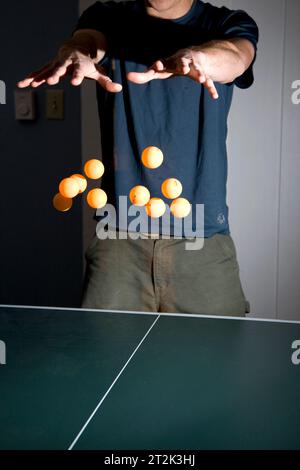 Ein Mann gibt vor zu zeigen, dass er 10 Ping-Pong-Bälle gleichzeitig schweben kann. Stockfoto
