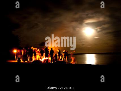 Eine Gruppe versammelte sich um ein Lagerfeuer am Ufer des Sebago Sees. Stockfoto