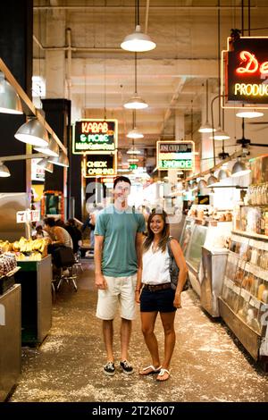 Ein Paar lächelt und schaut in die Kamera in einem Indoor-Markt in der Innenstadt von Los Angeles, der frische Produkte verkauft. Stockfoto