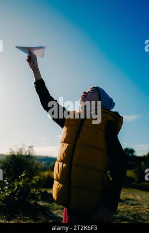 Ein Junge fliegt ein Papierflugzeug in den Himmel Stockfoto