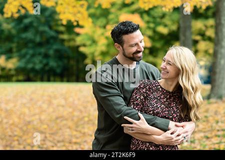 Ehemann und Ehefrau umarmen sich, sehen einander lächelnd an Stockfoto