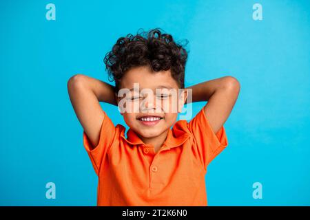 Foto des ruhigen Jungen, der schlafende Hände über Kopf isoliert auf blauem Hintergrund schläft Stockfoto