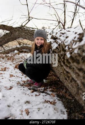 Glückliches Mädchen, das im Winter im schneebedeckten Wald lächelt Stockfoto