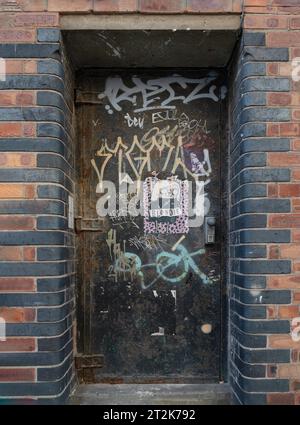 Liverpool, Großbritannien - 9. Oktober 2023 - Graffiti an einer alten Metalltür an der Ziegelwand in der Seel Street, Eisentür mit Graffiti bedeckt, Urban Art Graffiti, Space Stockfoto