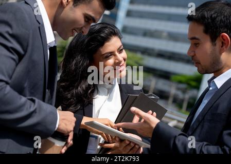 Asiatisches Business-Team in Firmenkleidung trifft sich und spricht draußen in der Stadt Stockfoto