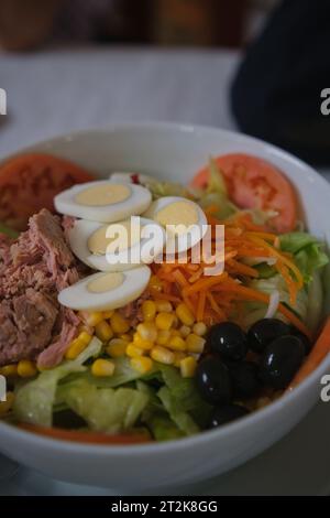 Köstlicher und frischer gemischter Salat mit Thunfisch, Tomaten, hartgekochten Eiern, Salat, Zuckermais, geriebene Karotten und schwarze Oliven. Stockfoto