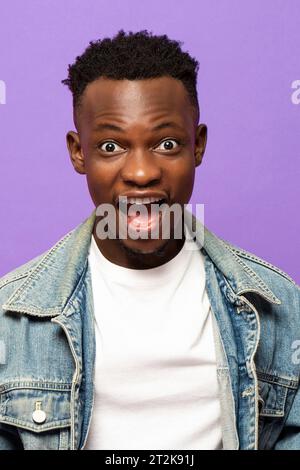 Junger afrikanischer Mann, der überraschtes Gesicht mit knallenden Augen in isoliertem lila Farb-Studio-Hintergrund ausdrückt Stockfoto