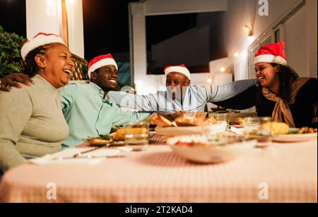 Glückliche afrikanische Familie, die Spaß beim gemeinsamen Essen während der Weihnachtszeit hat - Weihnachtskonzept - Hauptfokus auf Vatergesicht Stockfoto
