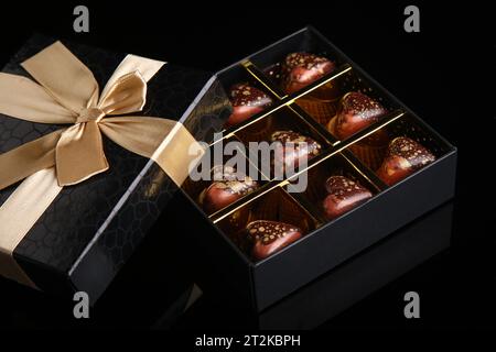Herzförmige bemalte Luxus handgemachte Bonbons in einer Geschenkbox auf schwarzem Hintergrund. Schokolade zum Valentinstag. Stockfoto