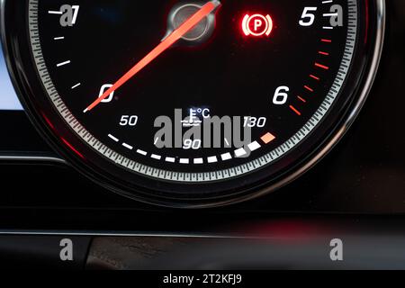 Modernes, digitales Wasser- oder Kühlmitteltemperaturmessgerät mit Fahrzeugbeleuchtung. Nahaufnahme, Drehzahlmesser oben, keine Leute. Stockfoto
