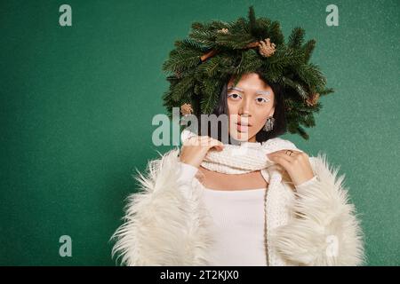 Winterschönheit, asiatische Frau mit weißem Make-up und natürlichem, kranzverstellendem Schal unter fallendem Schnee Stockfoto